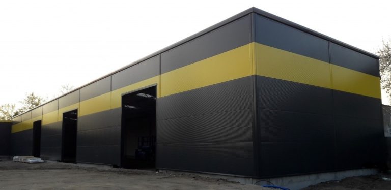 Czarna elewacja magazynu o pow. 520 m2 z żółtym pasem i trzema bramami przemysłowymi